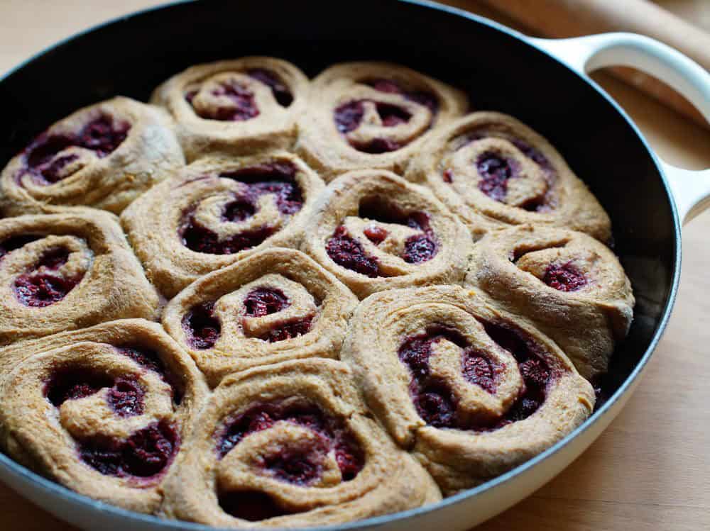 baked Lemon Raspberry Sourdough Sweet Rolls in a white cast iron pan