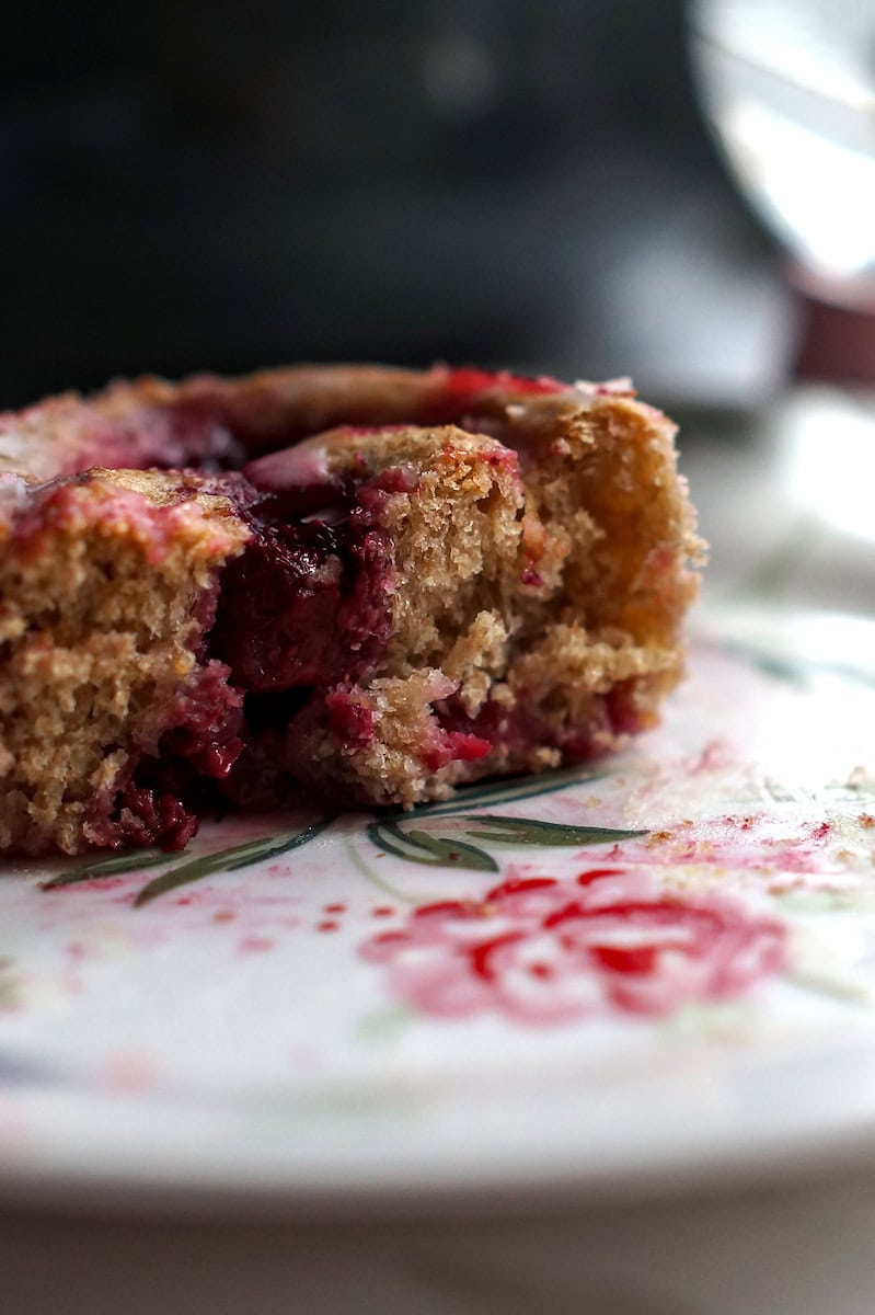 closeup of split roll on a flowery dessert plate, showcasing the flaky tender crumb and deep red raspberry filling