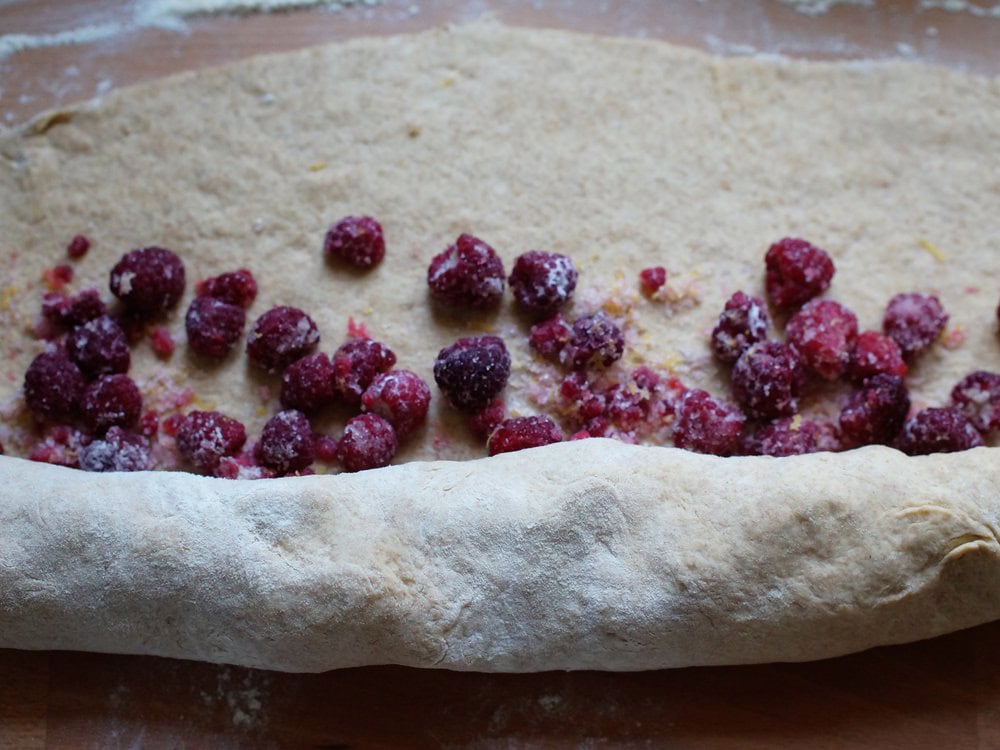closeup of frozen raspberry filling getting rolled up into the dough