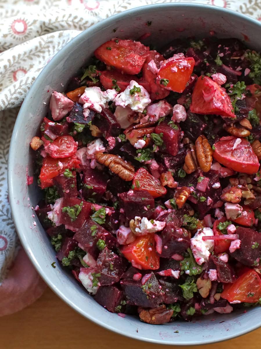 beet and blood orange salad in a pale blue bowl surrounded by a white and pink tea towel