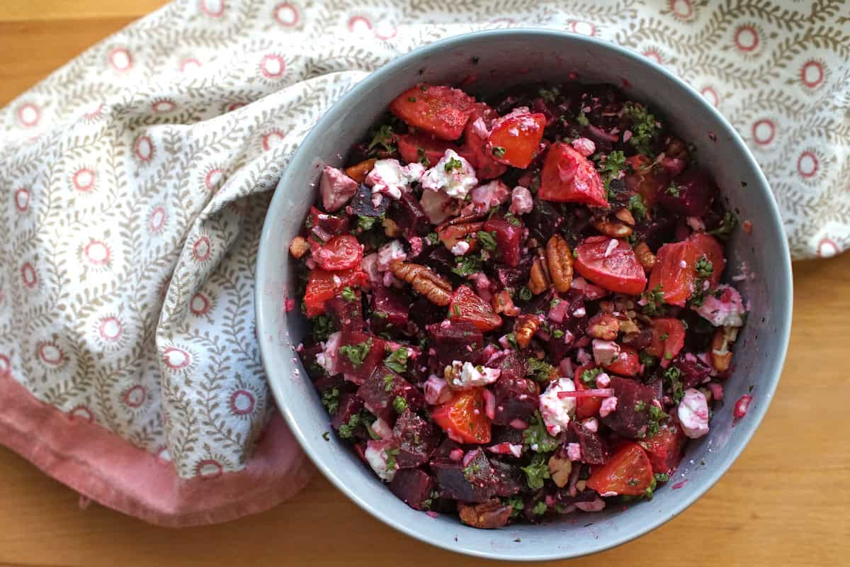 beet and blood orange salad in a pale blue bowl surrounded by a white and pink tea towel