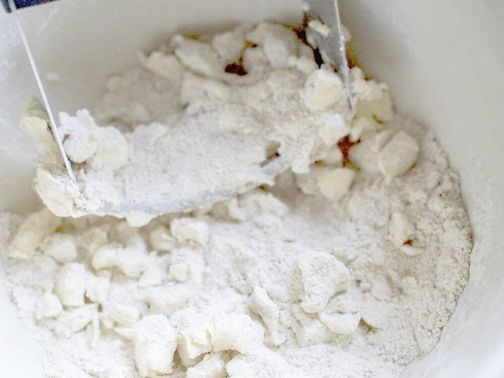 closeup of butter being cut into flour with a pastry blender, showcasing the large butter cubes being just broken down