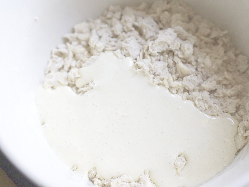 closeup of sourdough starter being poured on top of the butter and flour mixture