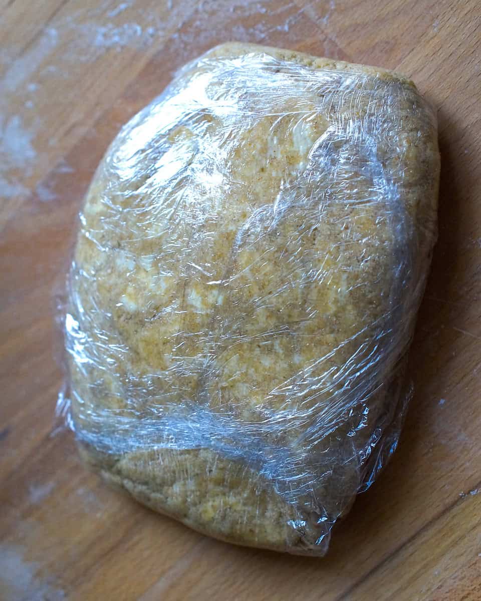 closeup of finished sourdough pie crust dough wrapped in plastic wrap