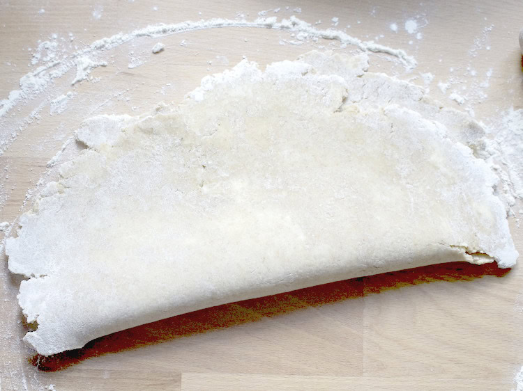 sourdough pi crust dough folded in half on a floured wooden countertop