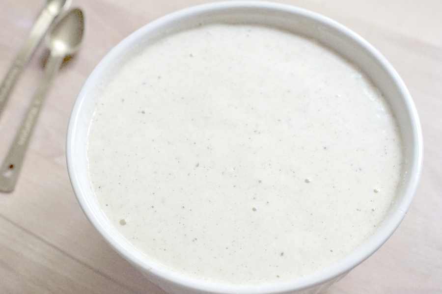 Closeup of pancake batter in a white ceramic bowl. It's frothy and bubbly and reaches all the way to the top of the bowl.