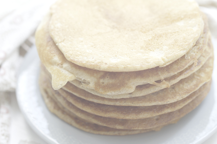 A stack of golden brown All-Discard Sourdough Pancakes on a light blue plate. You can see the fluffy, light texture of the finished pancakes.