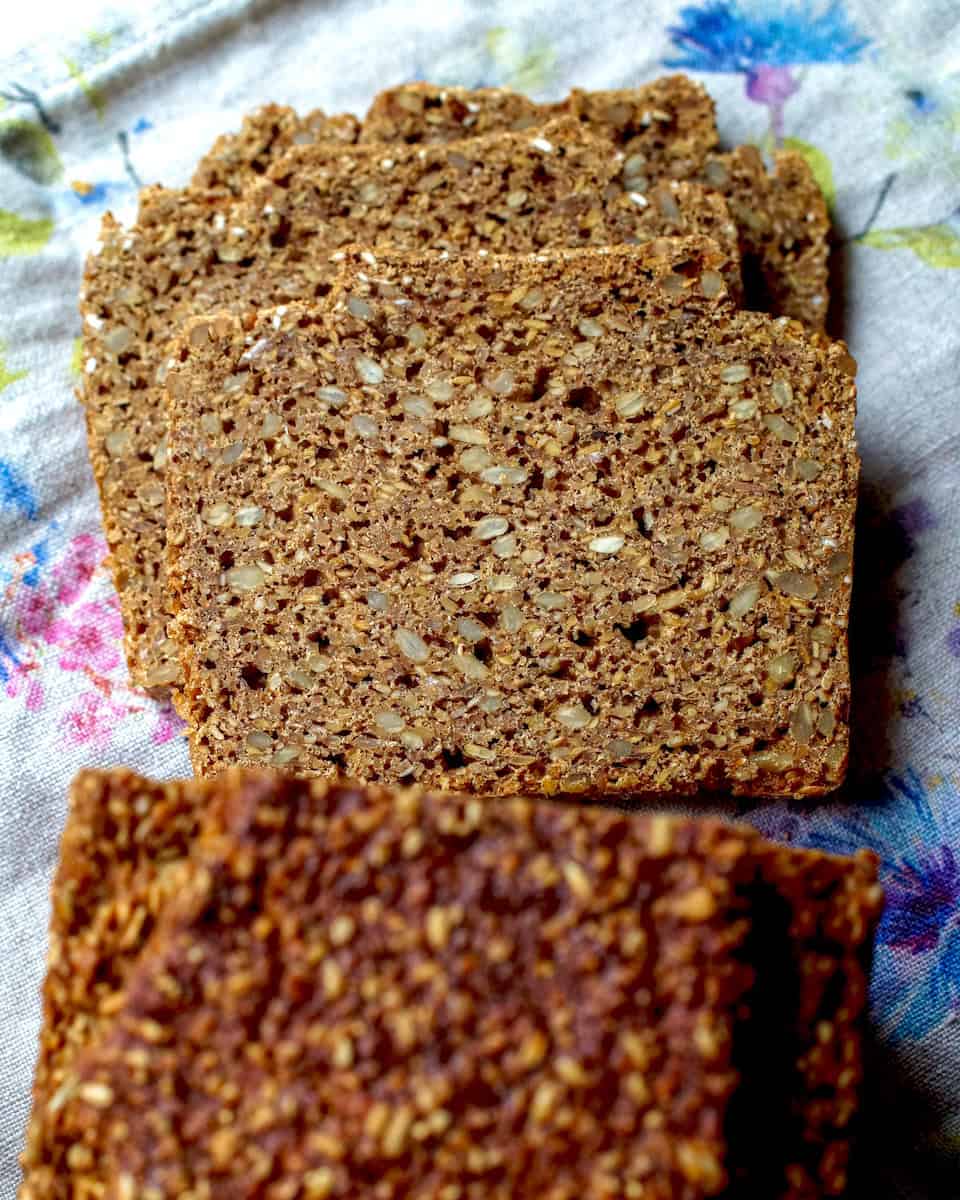 Slices of authentic German black bread on a floral dish cloth.