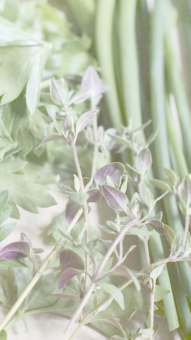 fresh herbs including parsley, chives, and thyme on a wooden cutting board
