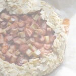 Overhead shot of bubbly Rhubarb, Strawberry and Almond Sourdough Galette, on a lined baking sheet with streaky sunlight