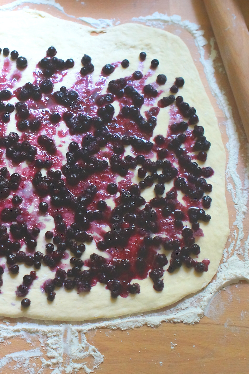 Sourdough Discard Bread Flour Dough, rolled out thinly, spread evenly with a lemon infused blueberry filling. Frozen wild blueberries are starting to release their magnificent purple juices across the dough.