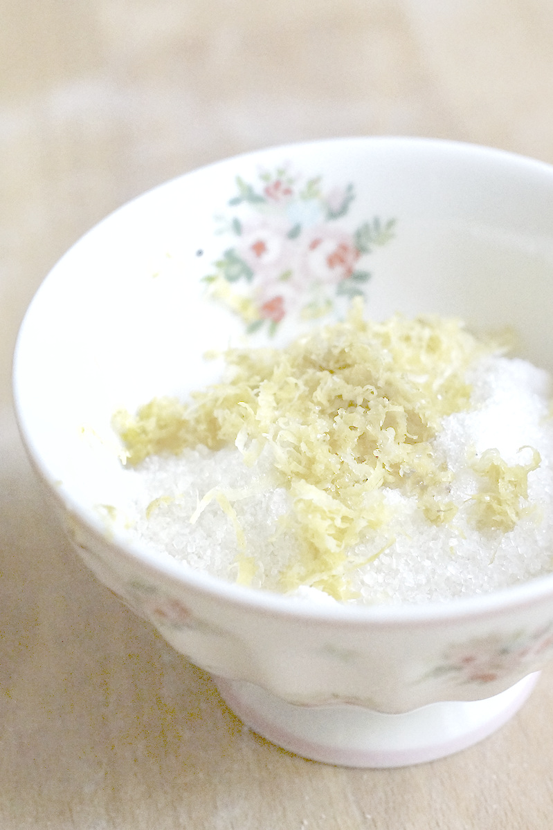 a small porcelain bowl with flowery decorations, filled with sugar and finely grated fresh lemon zest