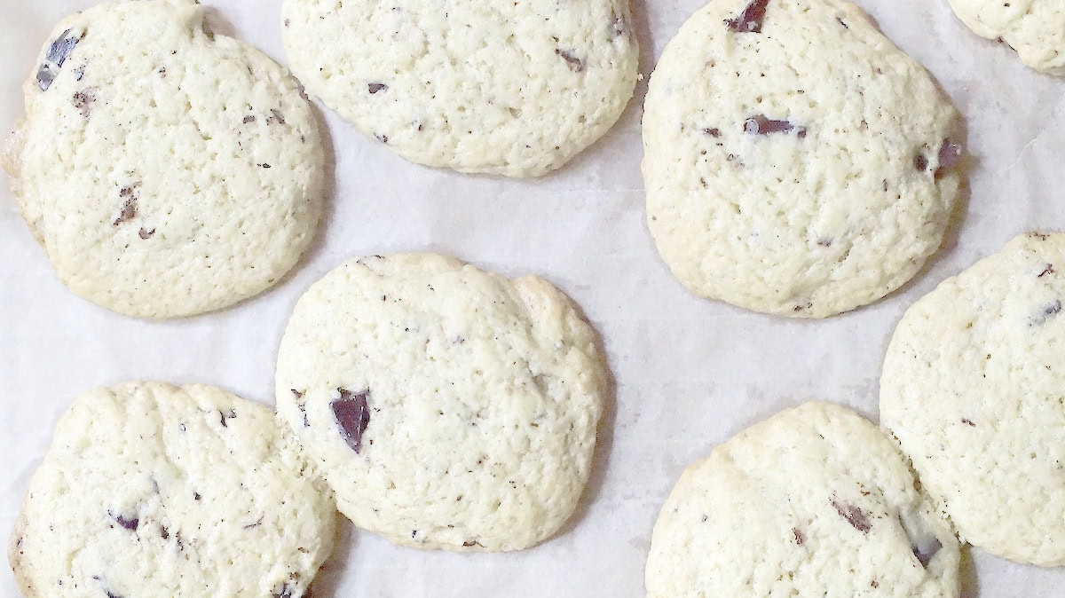 Sourdough discard chocolate chip cookies with melted chocolate chunks and golden brown edges cooling off on a parchment lined cooling rack.