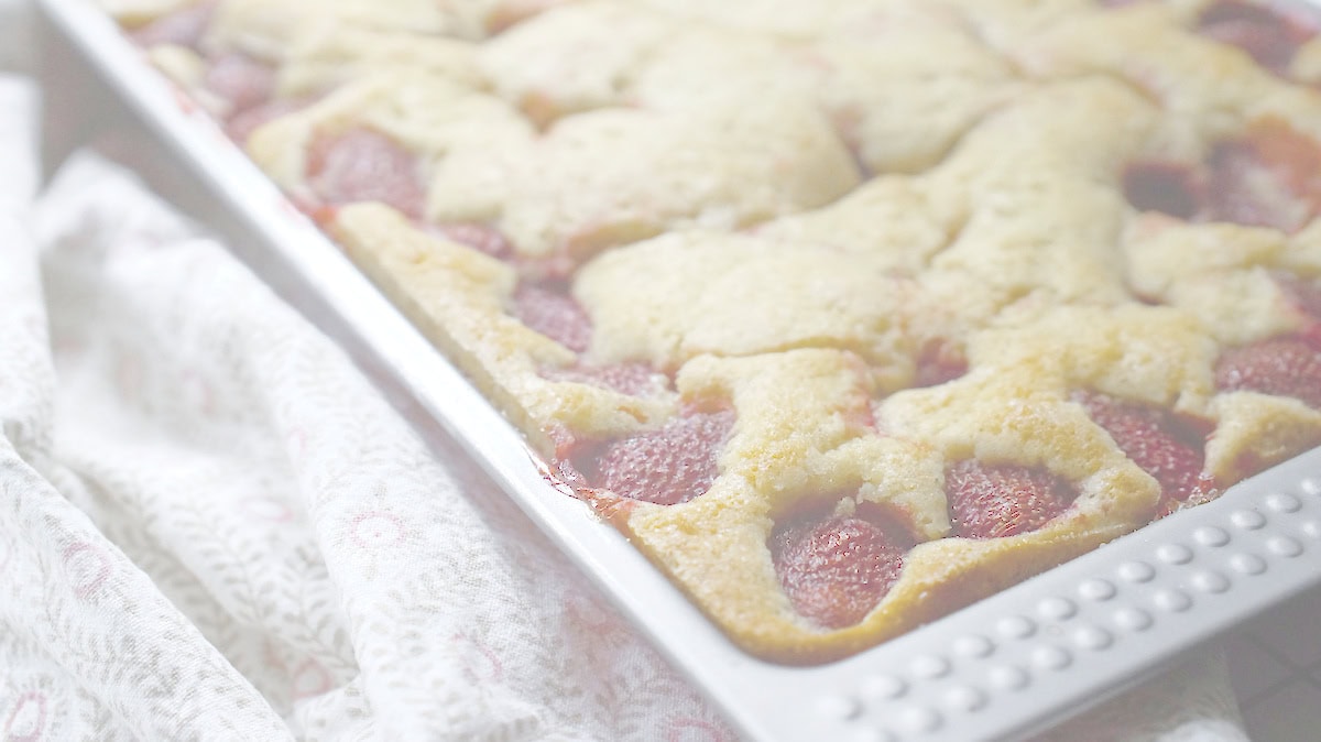 Close-up of baked strawberry sourdough cake in the pan, with jammy berries nestled in golden crumb.