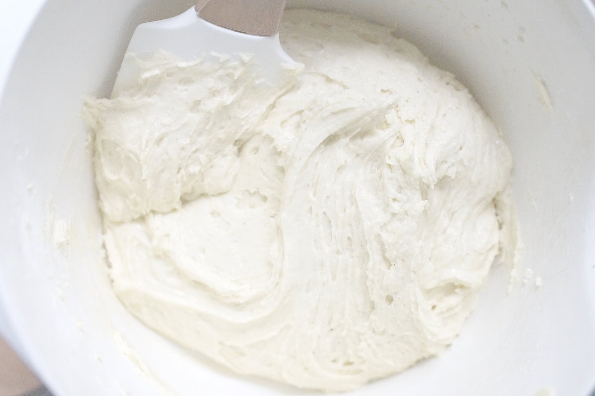 Thick, velvety discard batter in a white mixing bowl, stirred with a rubber spatula.
