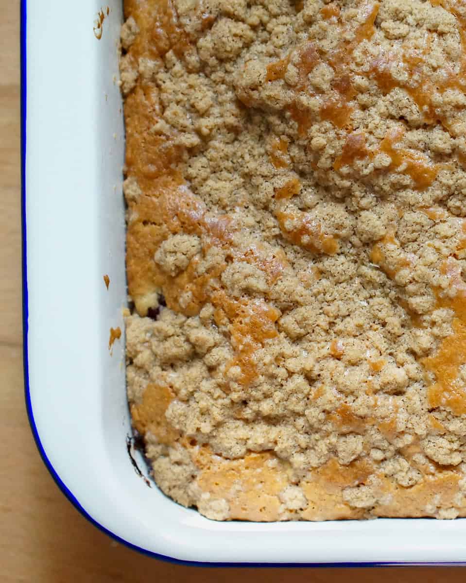 Closeup of sourdough cherry coffee cake - golden brown batter, riddled with cinnamon spiced crumbs.