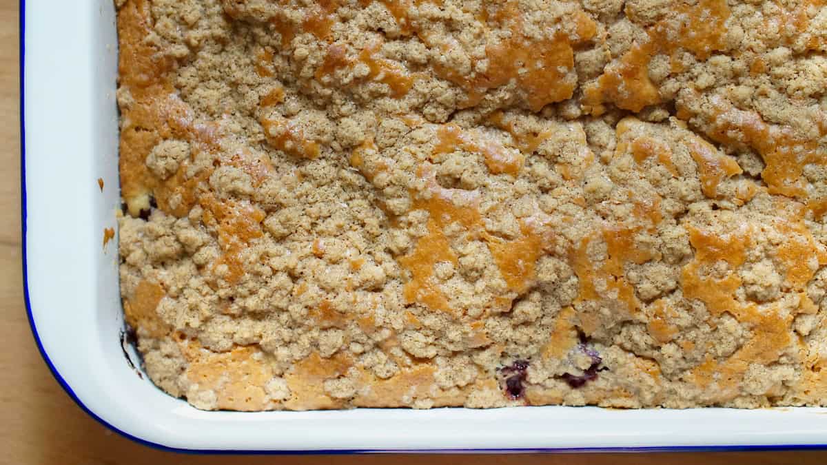 Closeup of sourdough cherry coffee cake - golden brown batter, riddled with cinnamon spiced crumbs.