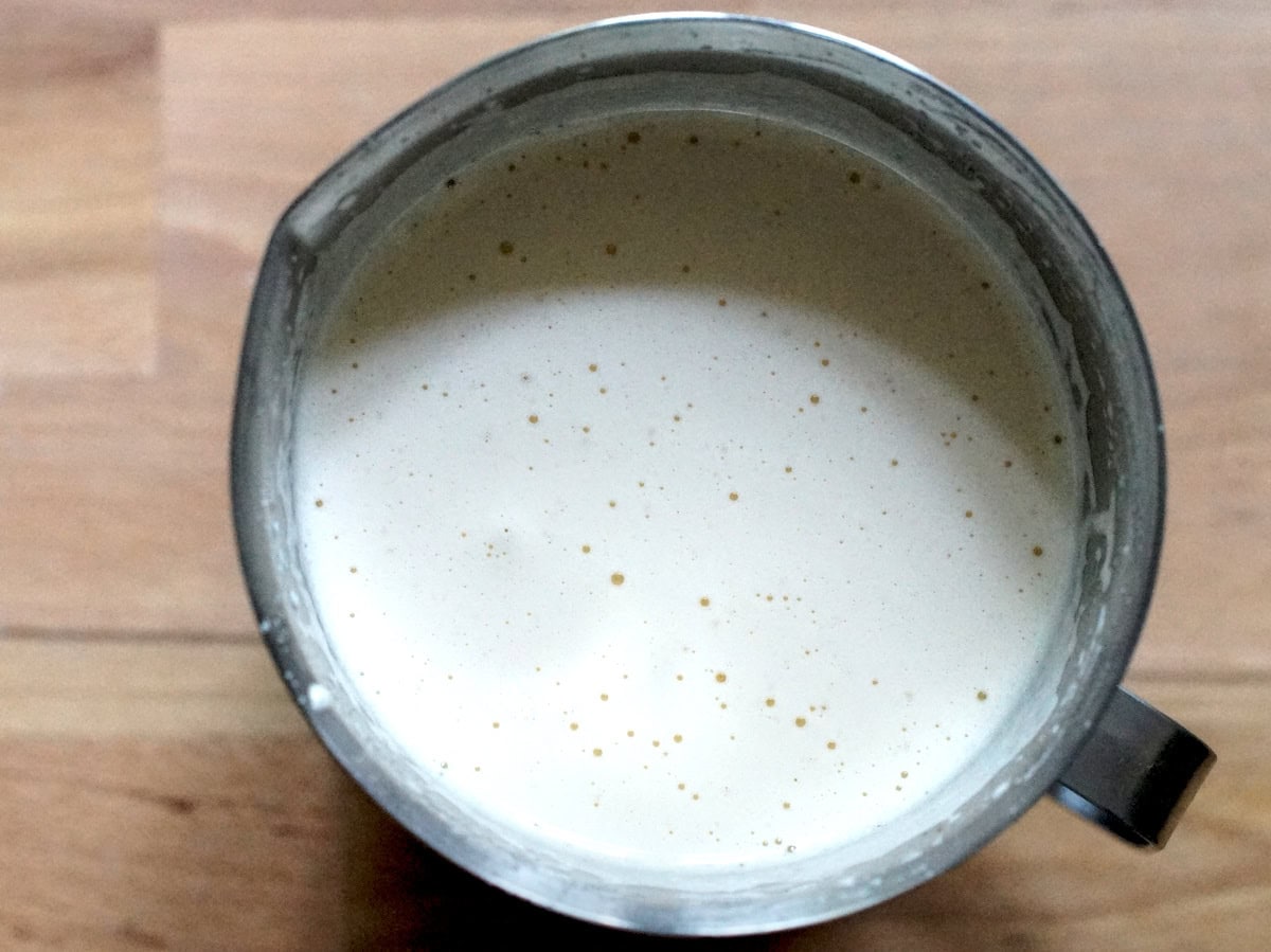 Pale and fluffy egg and sugar mix, sitting in a metal measuring jug.