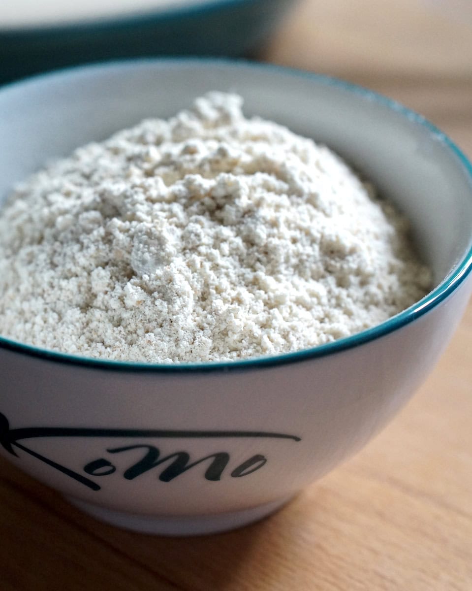 Closeup of ivory white, freshly milled einkorn flour in a small Komo-branded bowl with a dark blue rim.