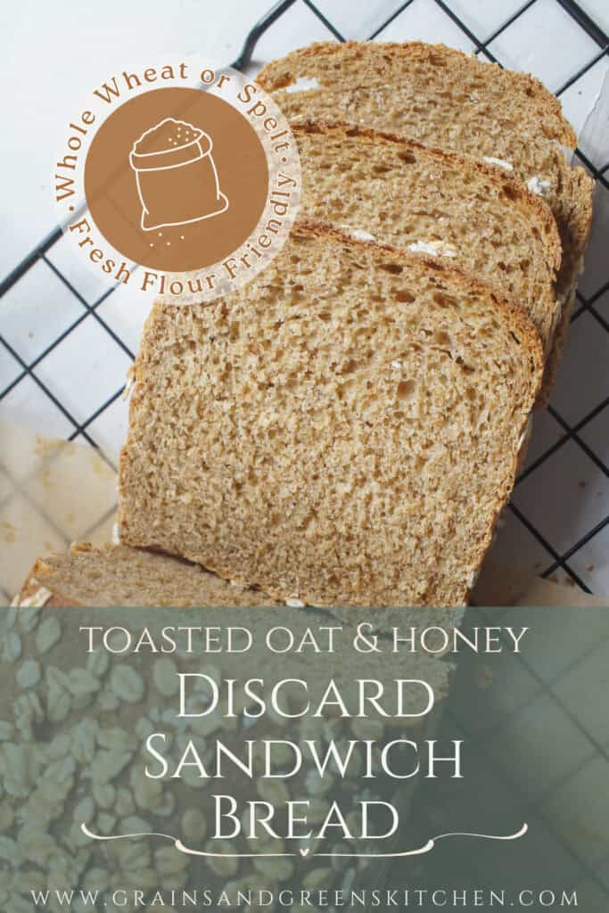 Slices of tender oat and honey whole wheat discard sandwich bread resting on a black wire rack. You can see the toasty oat crust and the fluffy crumb. The text overlay reads "toasted oat & honey discard sandwich bread, whole wheat or spelt, fresh flour friendly".