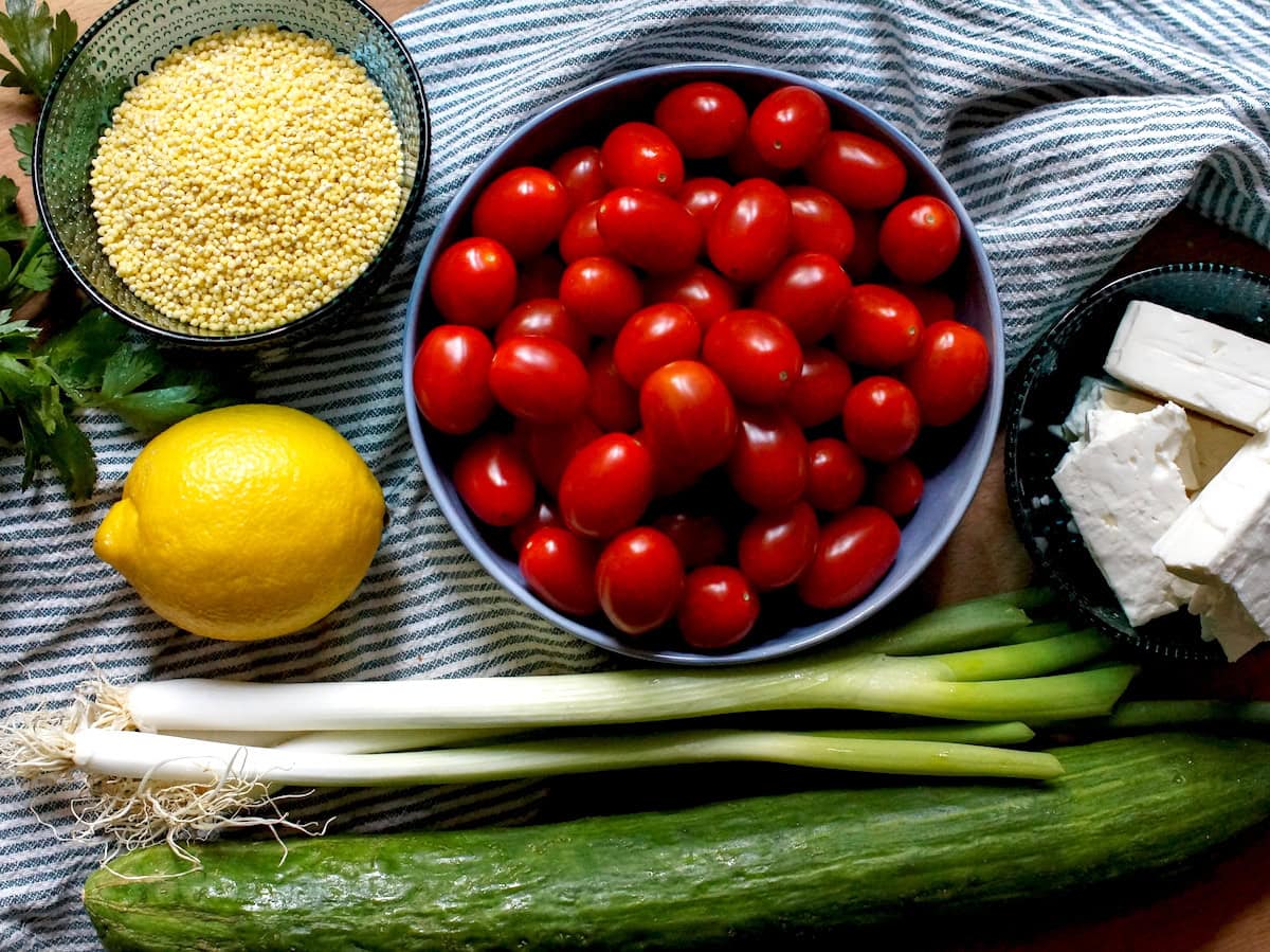 Fresh cherry tomatoes, cucumbers, green onions, lemon, millet, and feta cheese for millet tabbouleh.