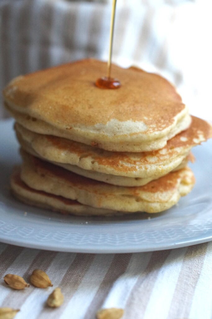 Closeup of a stack of gluten-free sourdough pancakes, with maple syrup drizzled on from above.