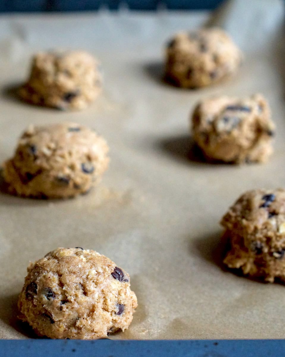 Spelt sourdough chocolate chip cookie dough rolled into balls, sitting on a lined baking tray.