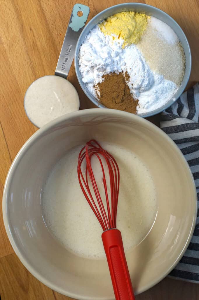 Wet and dry ingredients for crispy gluten free sourdough waffles laid out on a warm wooden kitchen counter.