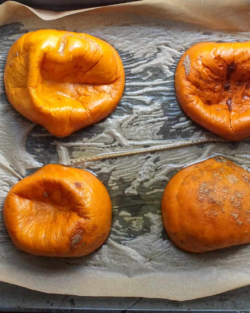 Roasted pumpkin halves on a parchment-lined baking tray,fresh from the oven and ready to blend into homemade pumpkin puree.