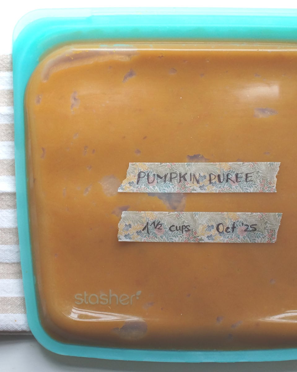 Homemade roasted pumpkin puree stored in a blue silicone freezer bag, ready for freezing.
