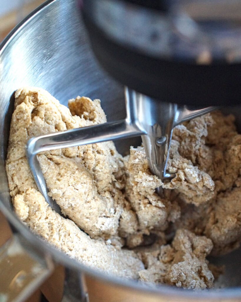 Shaggy whole wheat Swedish cinnamon roll dough, mixed with a paddle attachment in the bowl of a stand mixer.