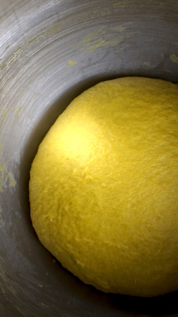 Slightly sticky sourdough lussekatter dough before bulk rise in a large stainless steel bowl.