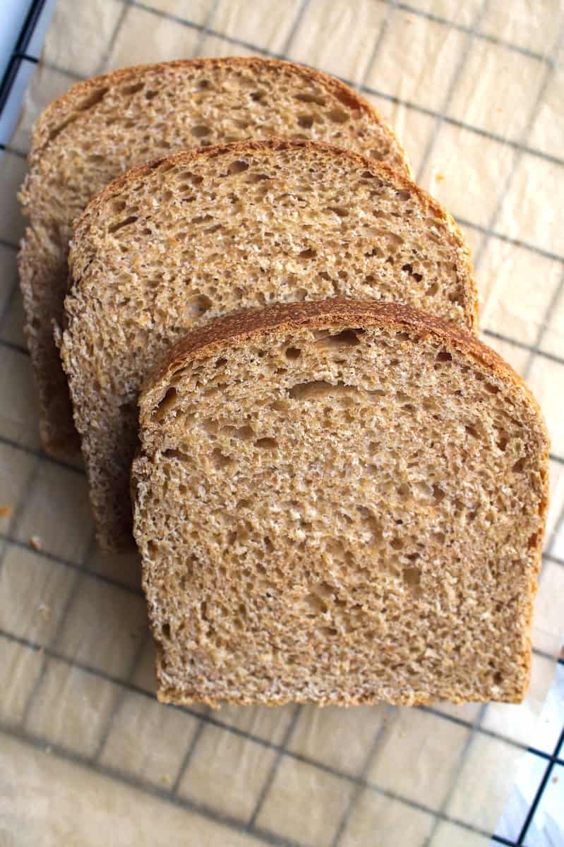 Three stacked slices of soft, fluffy European-style whole wheat sourdough sandwich bread made with fresh milled flour.