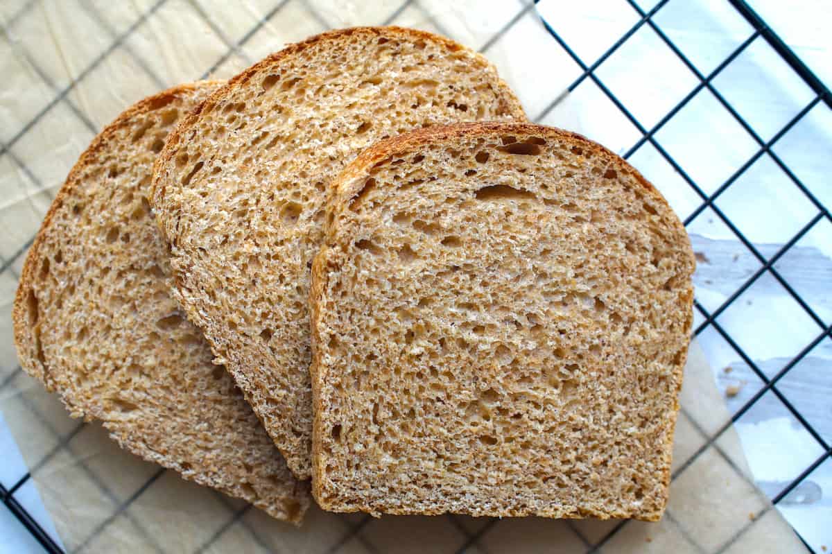 Three stacked slices of soft, fluffy European-style whole wheat sourdough sandwich bread made with fresh milled flour.